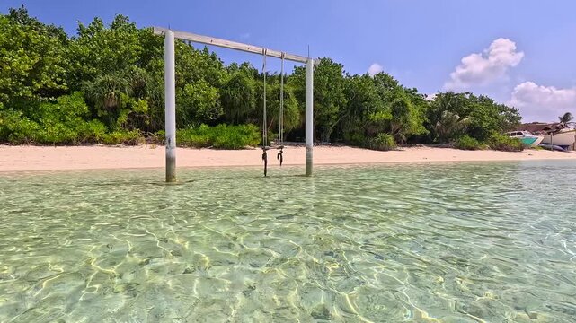 Empty white sand beach in Ukulhas Maldives with palm trees swings and turquoise water