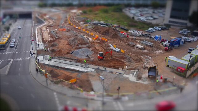 Construction site workers operating heavy machinery like an excavator and dumper. Building urban infrastructure. Creating a miniature city appearance with tilt-shift effect