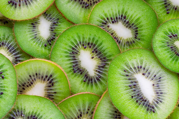 Slices of kiwi fruit arranged together showing the green flesh and black seeds, highlighting freshness and food preparation in a colorful display