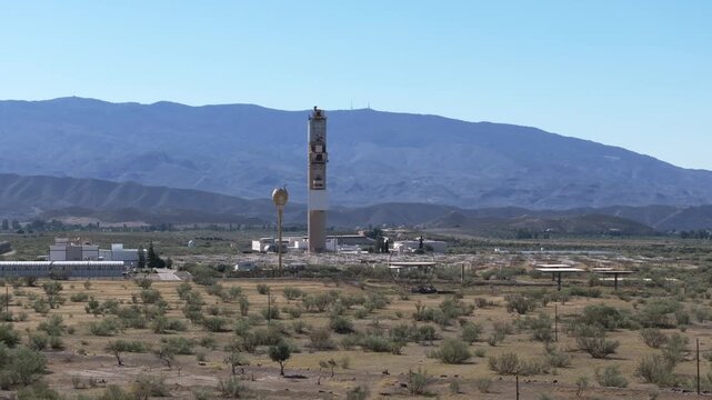 Distant drone shot of solar tower against blue mountains and arid valley near Almeria Spain clean energy infrastructure in Tabernas Desert