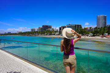 Fototapeta premium Vacation in Brazil. Rear view of young woman enjoying sight on belvedere in Maceio, Alagoas, Brazil.