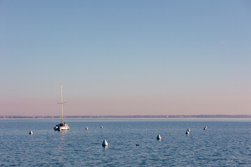 Sailboat anchored on calm blue water with navigation buoys and copy space © Nadia