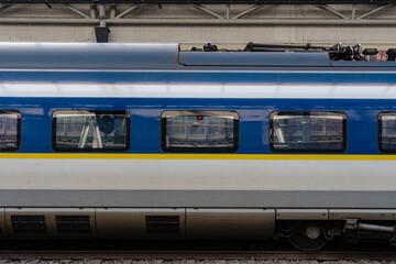 A blue and white train car sits idle on train tracks.