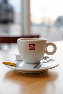 January 23, 2026, Amsterdam, Netherlands - Illy coffee cup with spoon, chocolate, and creamer on a wooden table