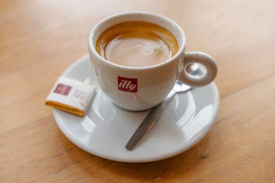 January 23, 2026, Amsterdam, Netherlands - Close-up of an Illy espresso cup with a spoon and sugar packet on a wooden table.