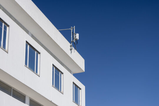 Modern white building exterior with telecommunication antenna on roof