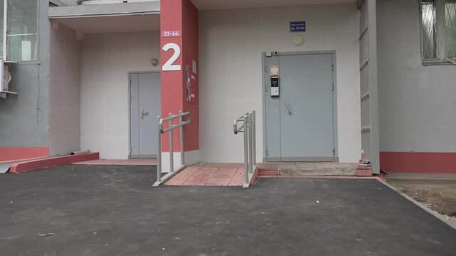 Apartment building entrance features heavy metal door and intercom system. Entrance with intercom marks residential building access point