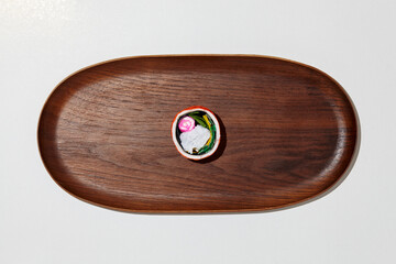 Set of paper sushi on a wooden plate over white background. Top view with copy space. Pure and fresh concept and composition.