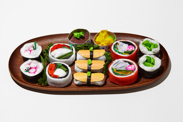 Set of paper sushi on a wooden plate over white background. Top view with copy space. Pure and fresh concept and composition.