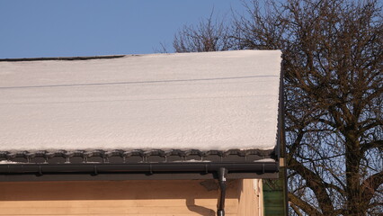 Dach domu ośnieżony oraz oświetlony promieniami słońca © tomo81