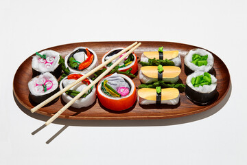 Set of paper sushi on a wooden plate over white background. Top view with copy space. Pure and fresh concept and composition.