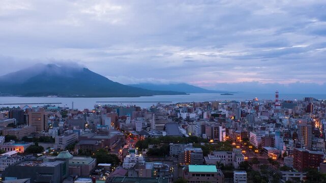 Kagoshima, Japan. View of mountain Sakurajima an active volcano. Aerial view of Kagoshima city in Japan at sunrise. Time-lapse with volcano eruption in the morning