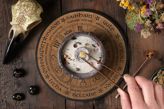 Wicca incense ritual - placing frankincense on glowing charcoal with tongs