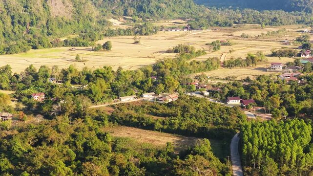 Aerial perspective of zipline over lush rainforest canopy in Vang Vieng, Laos with majestic mountain panorama in the background