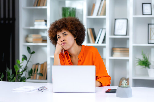Bored young woman sit at home office table look in distance unable to work at laptop, exhausted girl student feel unmotivated unwilling to study, distracted taking break. Dull monotonous job concept
