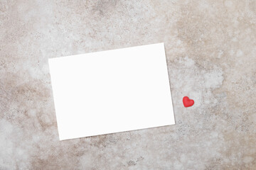 Blank wedding invitation or valentines day card mockup with small red heart decor, top view with copy space for text or card design