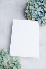 Blank greeting or invitation card mockup on gray stony background with blue vintage hydrangea flowers, perfect for wedding invitations or elegant messages