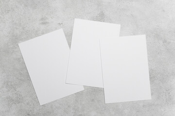 Three blank white cards on grey concrete background, ideal for greeting, invitation or flyer designs presentation, wedding cards, or minimalist stationery