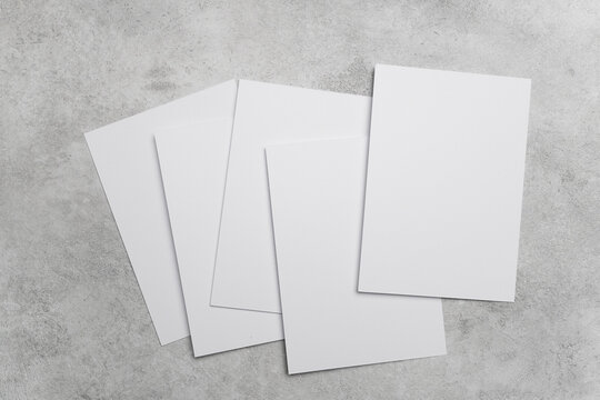 Stack of blank white cards on grey concrete background with copy space for greeting cards, wedding invitations or flyer designs presentation