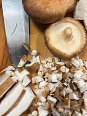 Fresh shiitake mushrooms on a wooden board. Whole mushrooms, sliced, and finely diced.