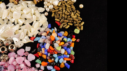 A variety of beads made of natural stone, glass, mother-of-pearl, ceramics and metal on a black background	