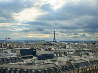 Panoramic top view of Paris, rooftops, Eiffel Tower and cloudy sky from the free observation deck on the roof of the Galeries Lafayette.