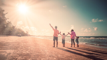 Fototapeta premium Happy family on the beach against blue sea and sky background at sunset. Holiday and summer travel concept