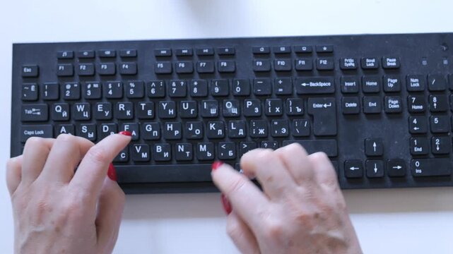 Person is typing on a keyboard with the letters A, B, C, D, E, F, G, H, I, J, K, L, M, N, O, P, Q, R, S, T,