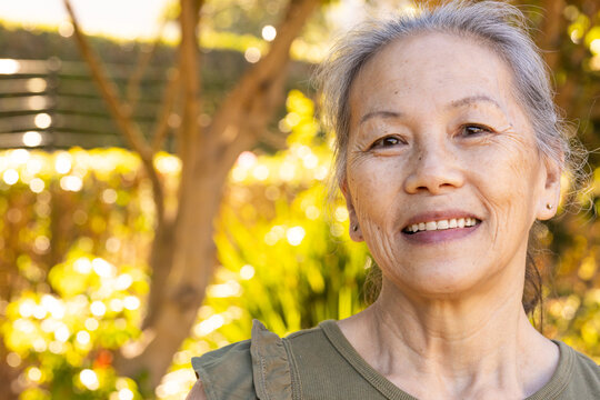 Olive-green sleeveless top catching warm golden sunlight against blurred garden with fence lines
