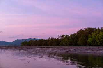 Sunrise view with colorful sky and the sea, with silhouette of the forest on the background