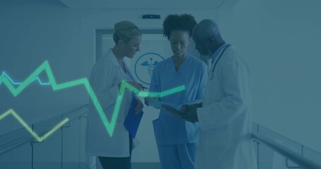 Discussing clinical team in lab coats, blue scrubs, reviewing charts in hospital corridor with ECG