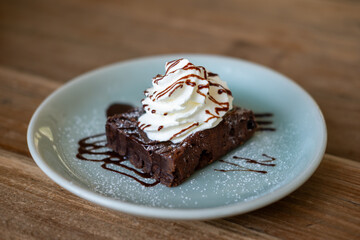 Close up of Brownie with whipped cream and chocolate sauce