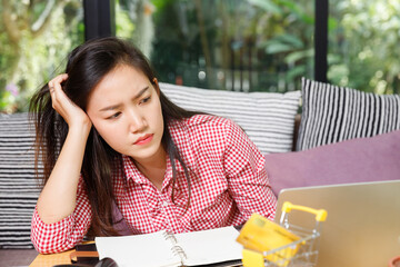 Stressed Asian business woman looking at laptop screen with worried face. Tired SME online seller having problem with sales or customer order.