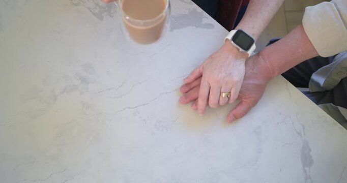 One is lifting mug above hands on countertop, other is adjusting, third is joining for comfort