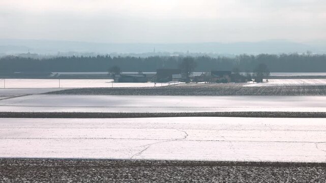 Winter landscape near Pocking Bavaria seen from observation tower with snowy fields and trees under cloudy sky