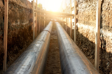 Industrial site showcasing the installation of pre-insulated steel pipelines in a trench. Ideal for: district heating project reports, energy efficiency articles, and utility maintenance news.