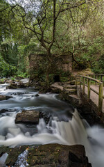 Obraz premium Waterfall under the bridge in summer time in verdes galicia