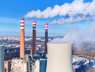Large thermal power plant with cooling tower and smokestacks producing electricity for urban area, ideal for: energy industry, power generation, emissions, utilities, infrastructure, energy transition