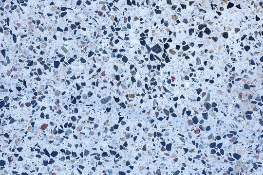 Modern terrazzo flooring texture featuring a polished concrete surface with dark marble chips and stone fragments. Seamless pattern for creative backgrounds, graphic and web projects.