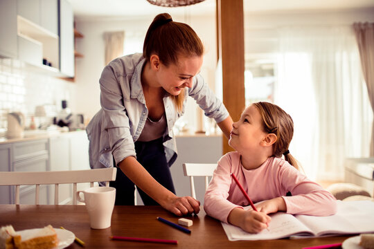 Mother helping daughter with homework at kitchen table
