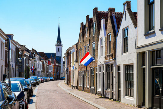 Traditional Dutch street with stepped gable houses and national flag in Brielle, South Holland, the Netherlands
