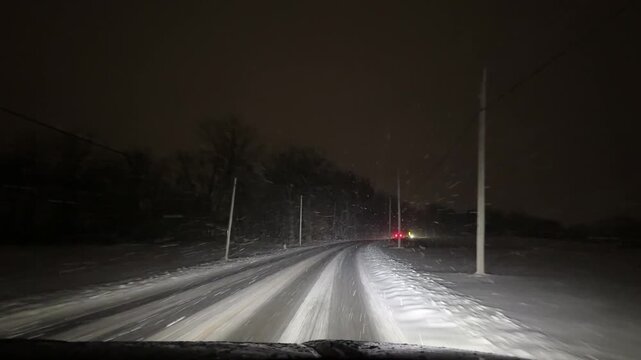 Driving at night during a snow storm on a rural highway with oncoming traffic 