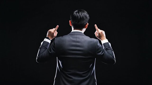 Man in suit pointing upwards against dark background