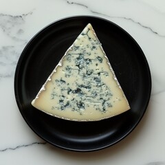 top down view of a black dinner plate with a slice of gorgonzola cheese