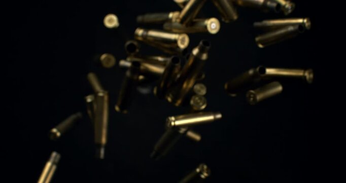 Slow Motion Macro Shot Of Brass Bullet Casings Burst On Black Background. Concept Of Ammunition, Industry And Impact
