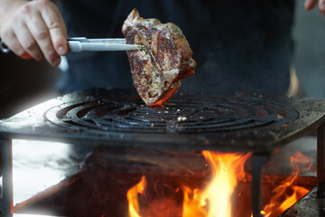 Beef steak grilling over open fire on barbecue grill with flames and smoke. Ideal for: food advertising, barbecue marketing, restaurant promotion, outdoor cooking, premium meat concepts.