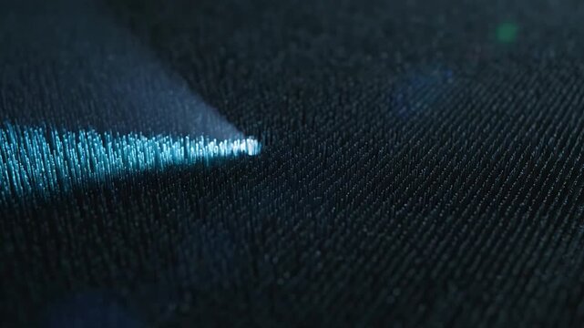 A sharp, vibrant beam of blue light dramatically strikes a dark, subtly textured surface at an acute angle, creating a luminous focal point.