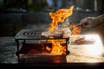 Grilling meat on open fire pit with dynamic flames for outdoor gourmet barbecue and catering services