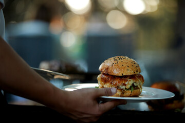 Waiter serving gourmet burgers at an outdoor venue. Ideal for: catering service websites, hospitality marketing brochures, and food event social media posts.