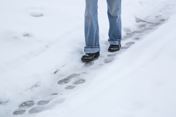 Danger of slipping. Person in chunky platform leather boots walking on snowy icey road
